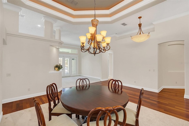 dining space featuring french doors, dark hardwood / wood-style flooring, a tray ceiling, crown molding, and a chandelier