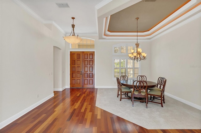 dining space with a notable chandelier, a raised ceiling, ornamental molding, and wood-type flooring