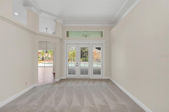 unfurnished room with light carpet, crown molding, a towering ceiling, and french doors