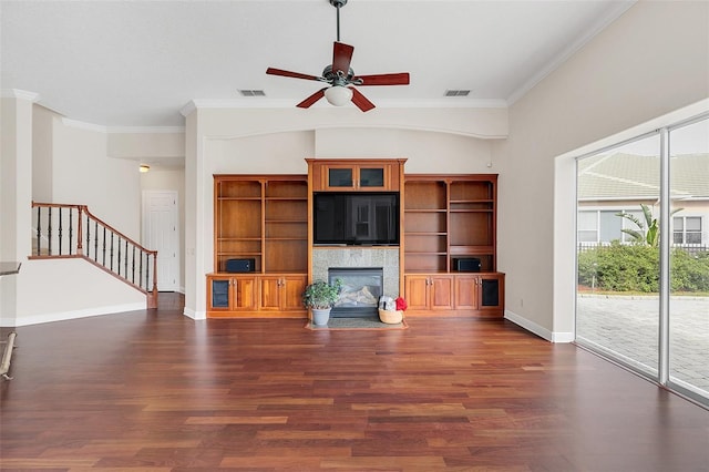 1610 Conway Isle Cir, Belle Isle, FL 32809 - unfurnished living room with dark wood-style flooring, crown molding, ceiling fan, stairway, and a tiled fireplace