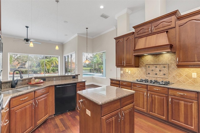 kitchen featuring dishwasher, premium range hood, sink, decorative light fixtures, and stainless steel gas cooktop