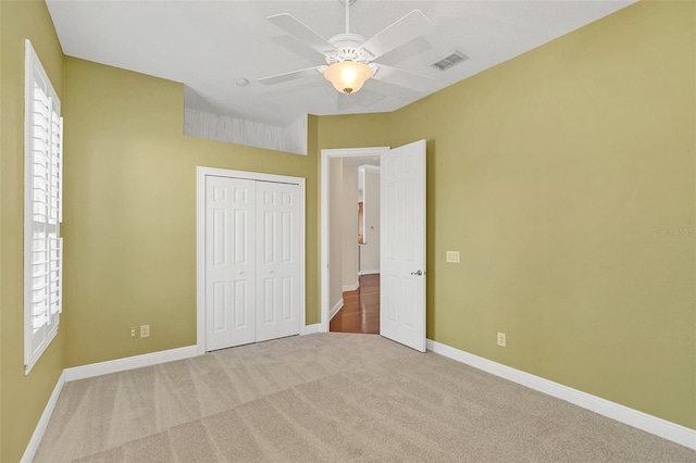 unfurnished bedroom with carpet flooring, multiple windows, a closet, and ceiling fan