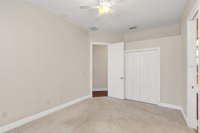 unfurnished bedroom featuring ceiling fan, light colored carpet, and a closet