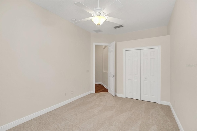 unfurnished bedroom with ceiling fan, light colored carpet, and a closet