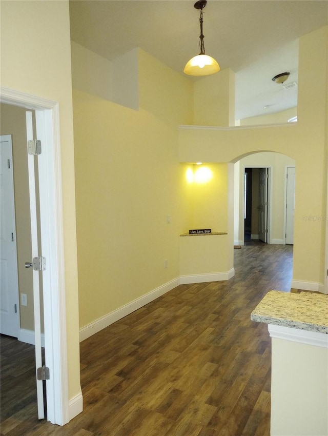 interior space with a towering ceiling and dark hardwood / wood-style floors