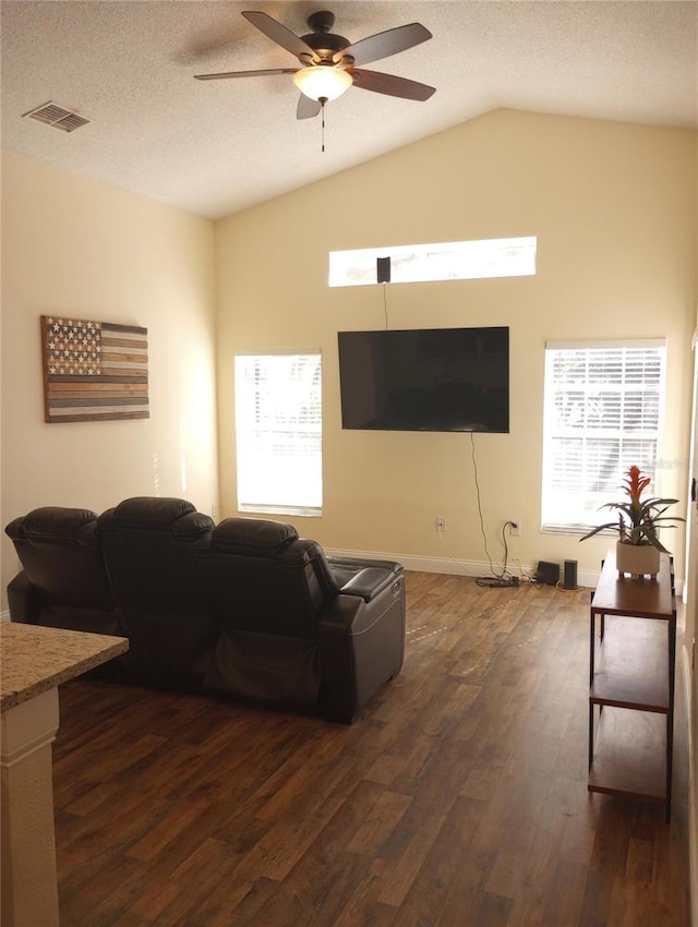 living room with a textured ceiling, ceiling fan, dark wood-type flooring, and vaulted ceiling