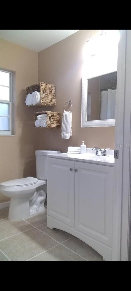 bathroom with tile patterned flooring, vanity, and toilet