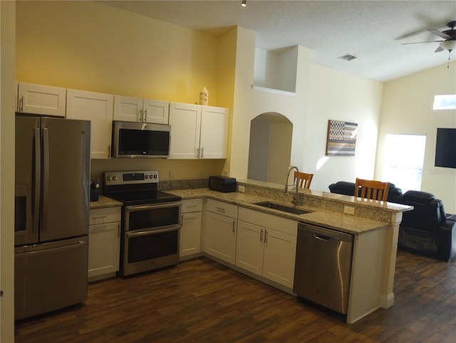 kitchen featuring sink, kitchen peninsula, light stone counters, white cabinetry, and stainless steel appliances