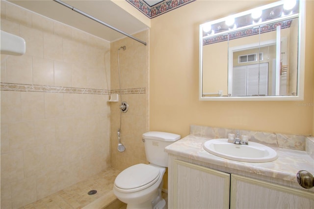 bathroom with vanity, toilet, and a tile shower