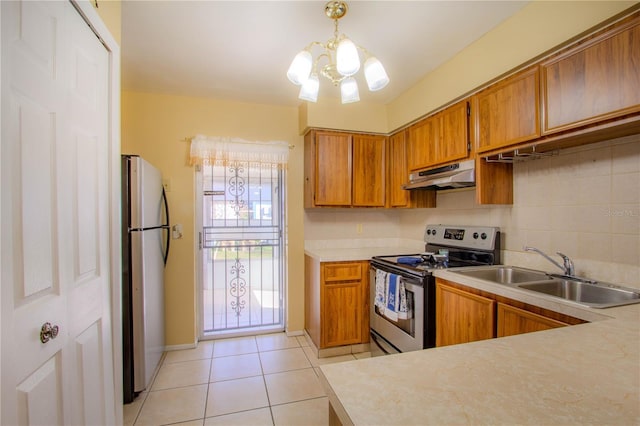 kitchen with appliances with stainless steel finishes, sink, a chandelier, hanging light fixtures, and light tile patterned flooring