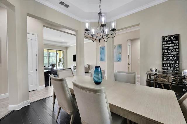 dining area with a chandelier, wood-type flooring, a raised ceiling, and ornamental molding