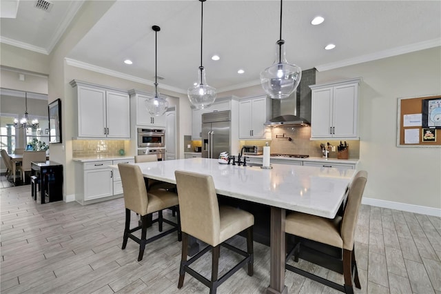 kitchen featuring white cabinets, hanging light fixtures, a large island with sink, and appliances with stainless steel finishes