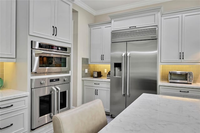 kitchen featuring appliances with stainless steel finishes, backsplash, light stone counters, and ornamental molding