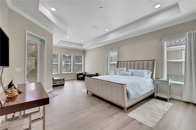 bedroom with ornamental molding, a tray ceiling, and light hardwood / wood-style floors