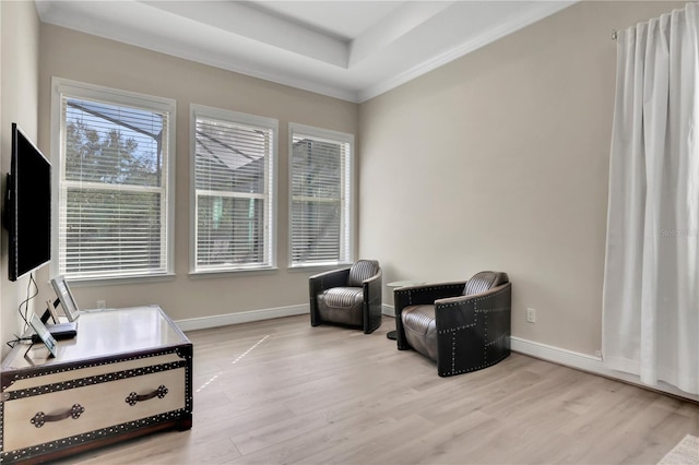 living area featuring a raised ceiling, ornamental molding, and light hardwood / wood-style flooring