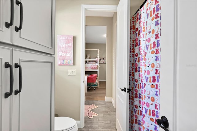 bathroom featuring hardwood / wood-style flooring, toilet, and walk in shower