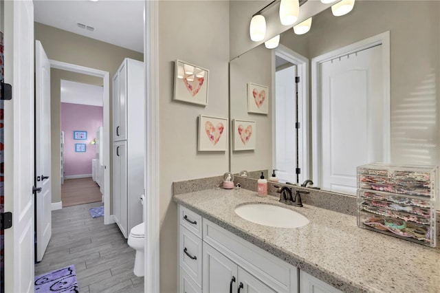 bathroom featuring wood-type flooring, vanity, and toilet