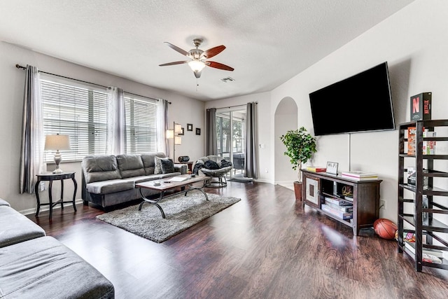 living room featuring ceiling fan, dark hardwood / wood-style flooring, and a textured ceiling