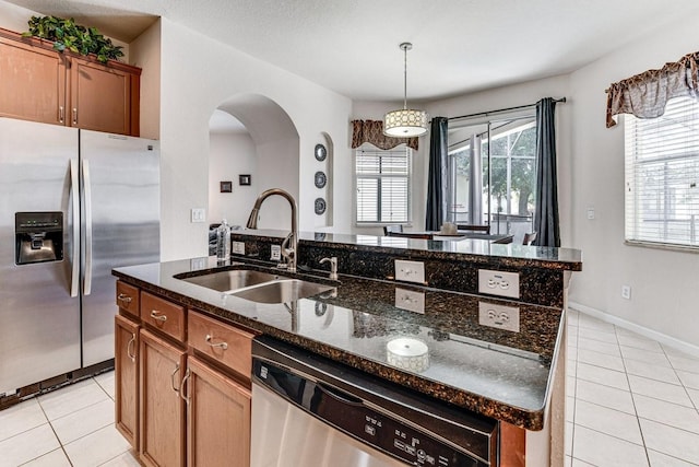 kitchen featuring a center island with sink, dark stone countertops, sink, and appliances with stainless steel finishes