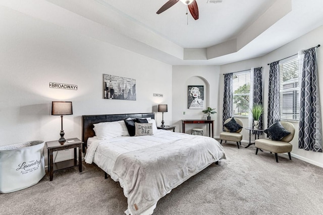 bedroom with a raised ceiling, ceiling fan, and carpet floors