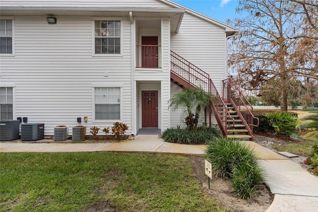 view of front of home with central AC unit and a front yard