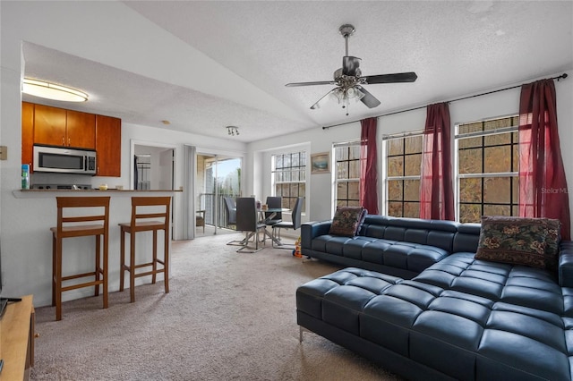 carpeted living room with a textured ceiling, ceiling fan, and vaulted ceiling