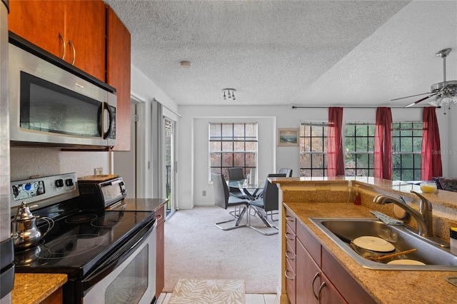 kitchen featuring ceiling fan, sink, stainless steel appliances, a textured ceiling, and light carpet