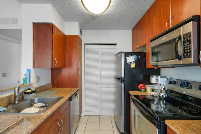 kitchen with a textured ceiling, light tile patterned flooring, sink, and appliances with stainless steel finishes