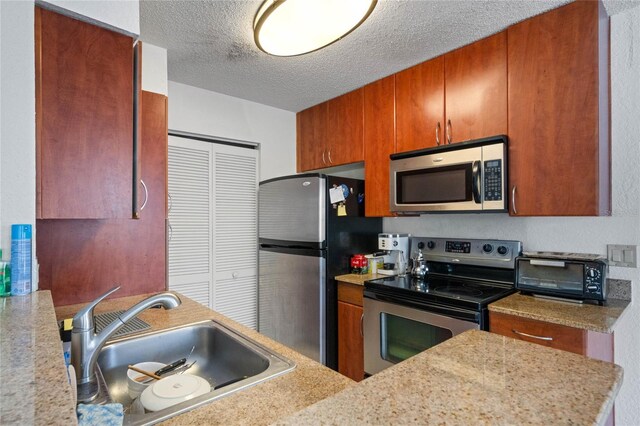 kitchen featuring a textured ceiling, sink, and stainless steel appliances