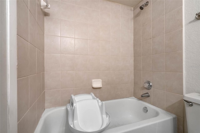 bathroom with toilet and tiled shower / bath