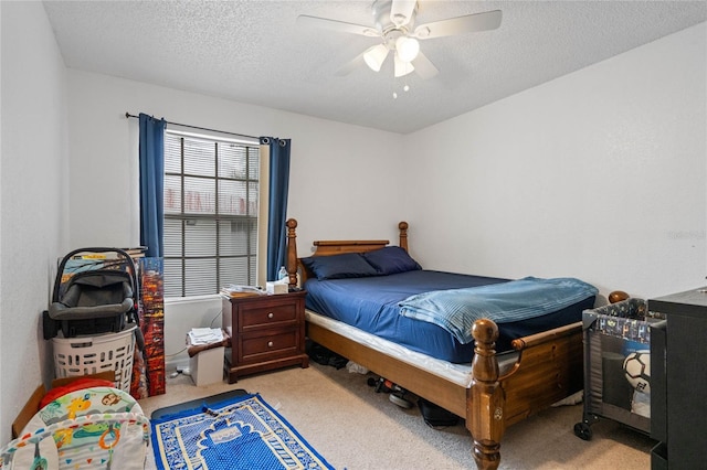 bedroom with ceiling fan, light colored carpet, and a textured ceiling