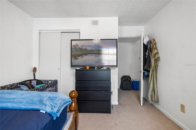 bedroom featuring a textured ceiling, light colored carpet, and a closet