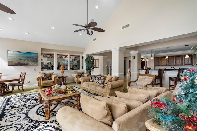 living room with ceiling fan, ornate columns, and high vaulted ceiling