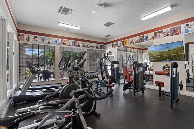 exercise room with ceiling fan and a textured ceiling