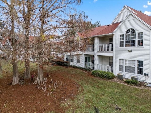 back of property featuring central AC and a lawn