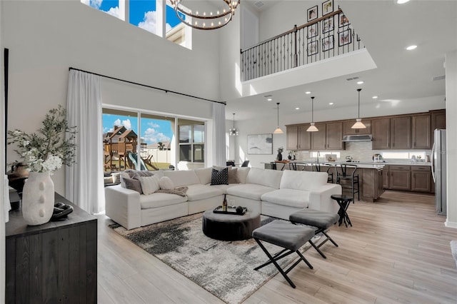 4360 Sunset Preserve Blvd, Orlando, FL 32820 - living room featuring plenty of natural light, a towering ceiling, a chandelier, and light wood-type flooring