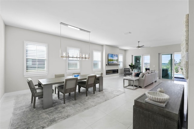 tiled dining area with a healthy amount of sunlight and ceiling fan with notable chandelier