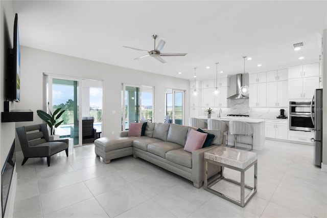 tiled living room with ceiling fan, a healthy amount of sunlight, and sink