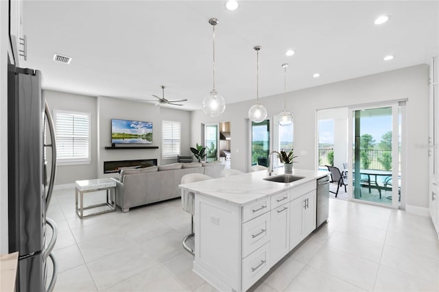 kitchen with white cabinetry, sink, ceiling fan, stainless steel appliances, and an island with sink