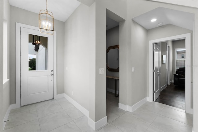 entryway with a chandelier, light tile patterned floors, and a healthy amount of sunlight