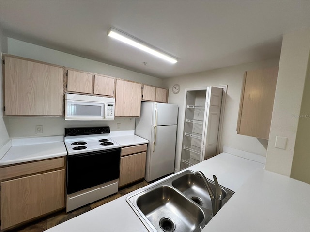 kitchen with light brown cabinetry, sink, and white appliances