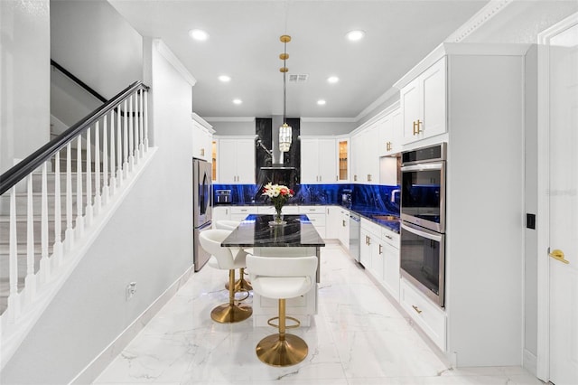 kitchen with white cabinetry, stainless steel appliances, tasteful backsplash, decorative light fixtures, and a kitchen island