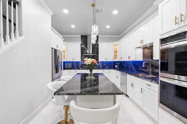 kitchen featuring sink, a center island, stainless steel appliances, tasteful backsplash, and dark stone counters