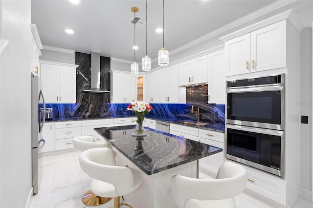 kitchen featuring a breakfast bar, backsplash, sink, wall chimney exhaust hood, and appliances with stainless steel finishes