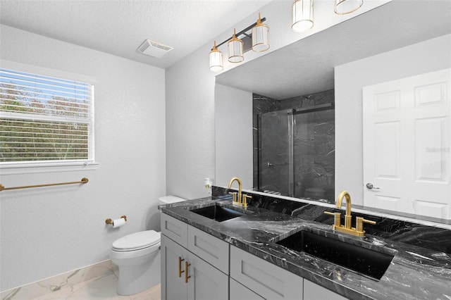 bathroom with a textured ceiling, vanity, toilet, and a shower with shower door