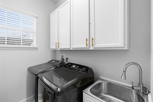 clothes washing area with cabinets, washer and clothes dryer, and sink