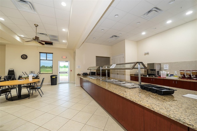 kitchen featuring light stone countertops, a drop ceiling, ceiling fan, and light tile patterned floors