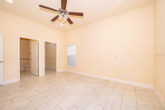 unfurnished bedroom featuring ceiling fan, ensuite bath, a walk in closet, and a closet