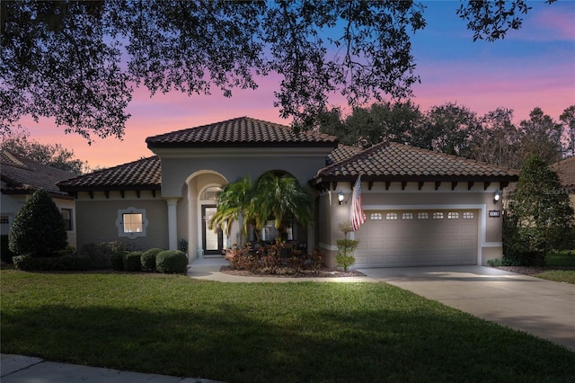 mediterranean / spanish-style house featuring a garage and a lawn