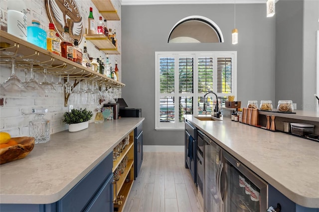 kitchen with sink, beverage cooler, blue cabinets, light hardwood / wood-style floors, and pendant lighting